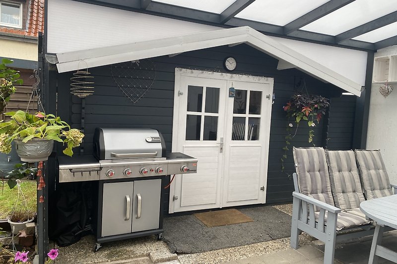 Überdachte Terrasse mit Gasgrill im eingezäunten Garten