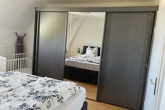 Schlafzimmer mit Spiegel-Kleiderschrank, Doppelbett und Babybett